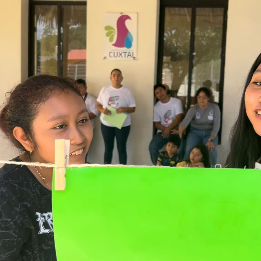 Niña sonriente frente a una pantalla verde de croma, acompañada de facilitadoras