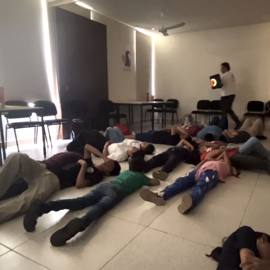 Niñas y niños recostados en el piso durante un juego de expresión corporal