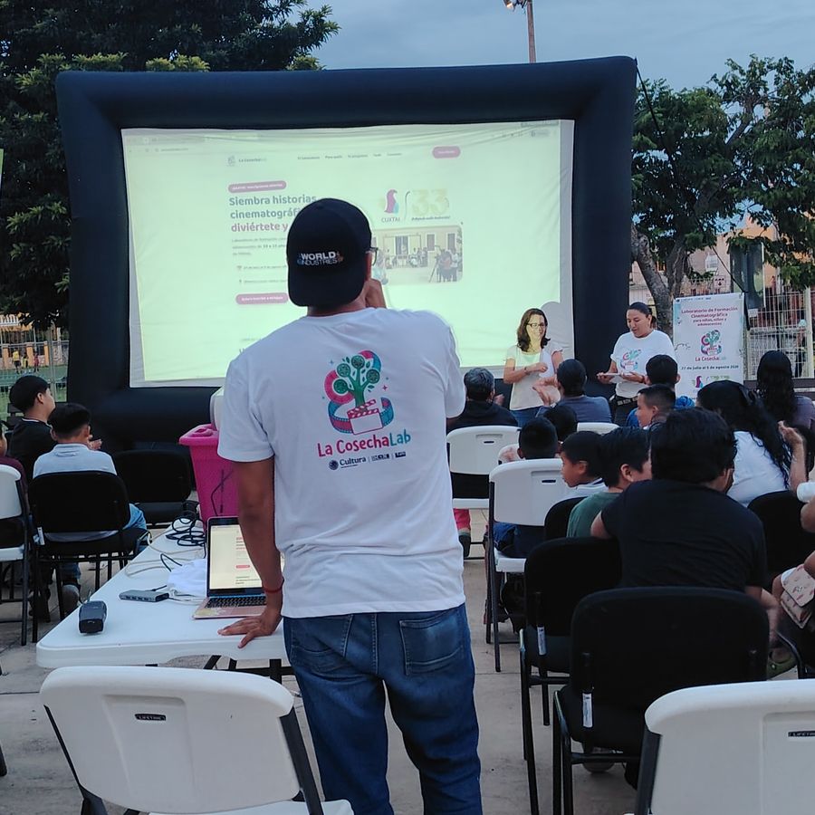 Niñas, niños y familias viendo una proyección en pantalla inflable al aire libre