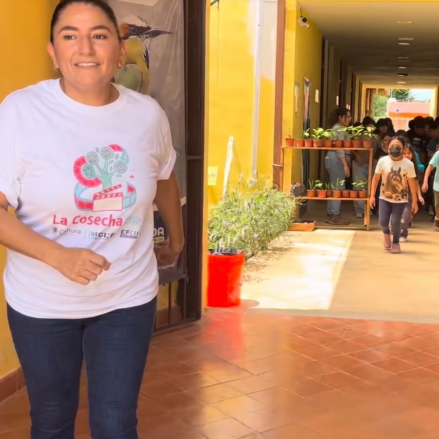 La facilitadora caminando por el pasillo mientras los niños corren detrás, sonriendo