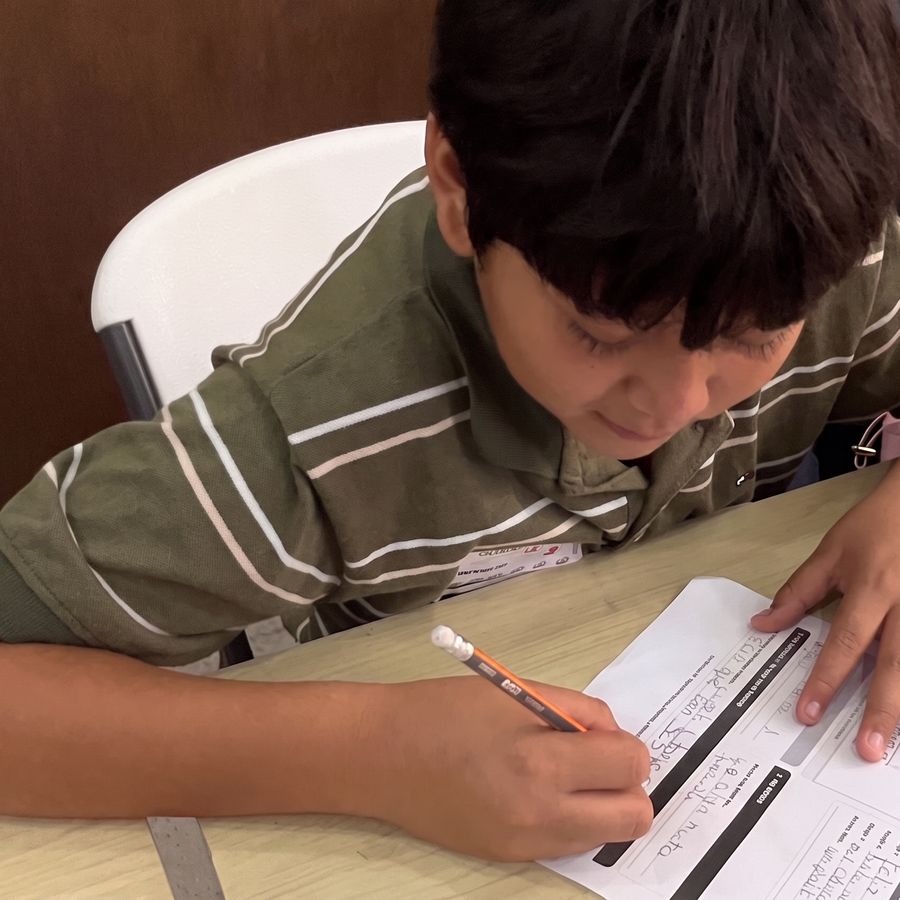 Niño llenando su ficha de personaje con lápiz y papel