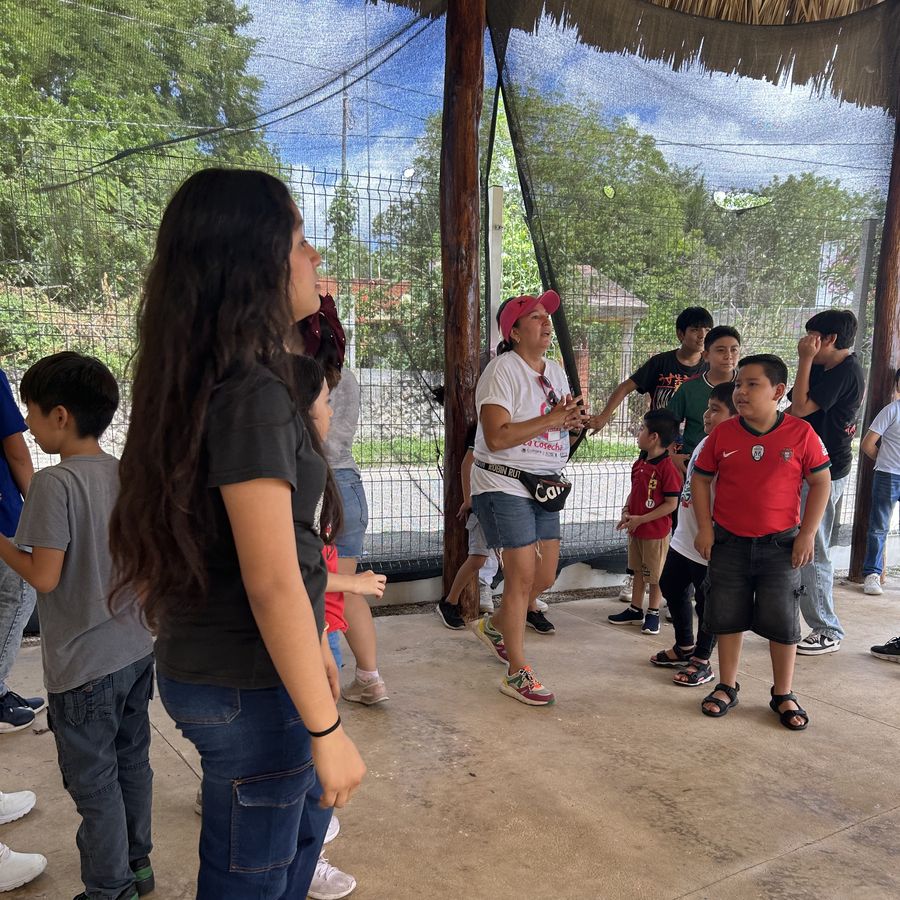 Facilitadora y niñas y niños formados afuera durante una actividad
